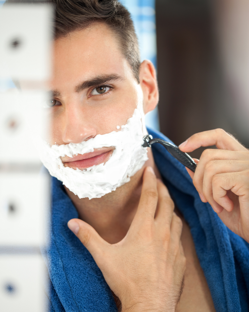 Get the perfect shave for men. Man shaves his face in the mirror.