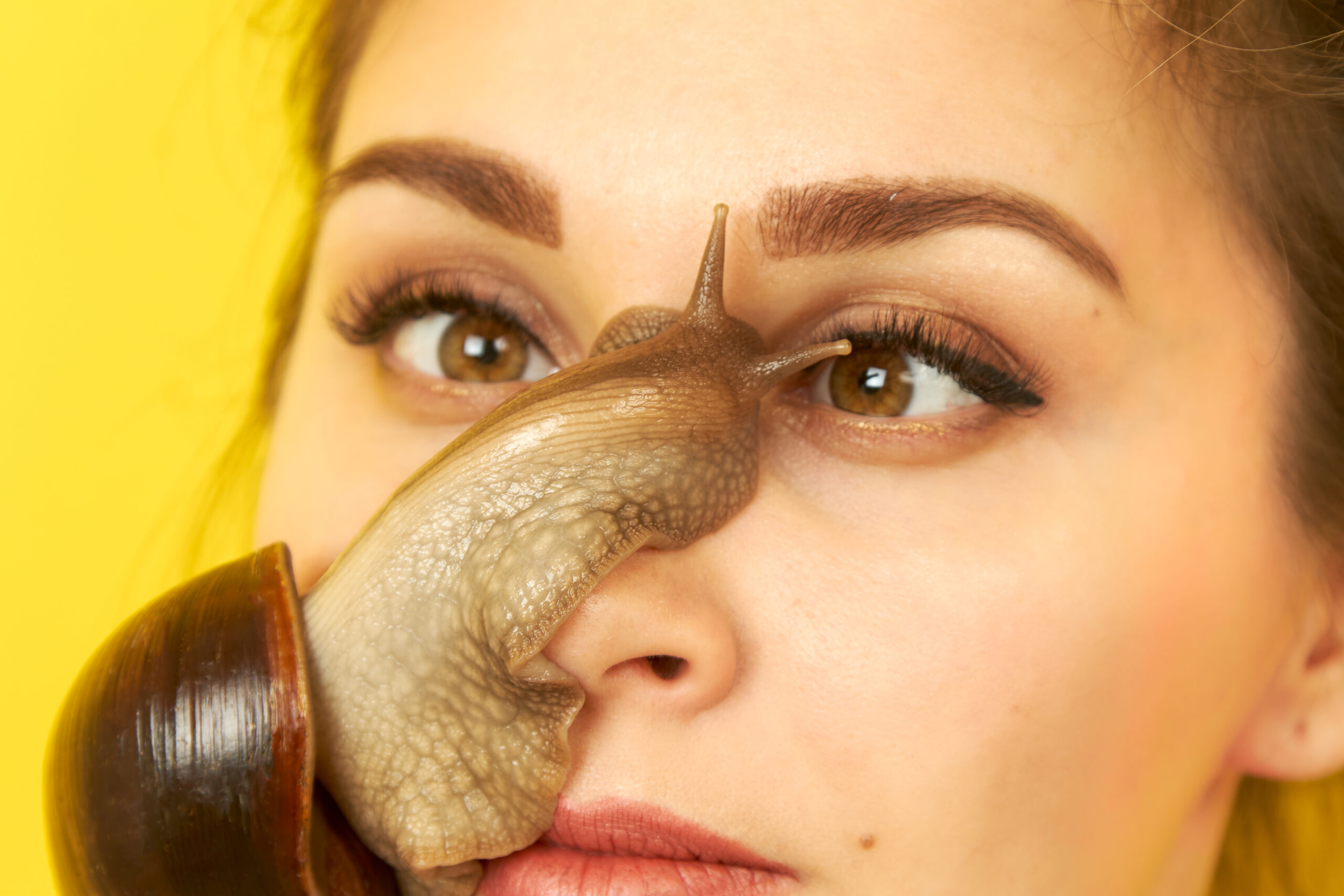 Close up of woman with slug on face. Yellow backround